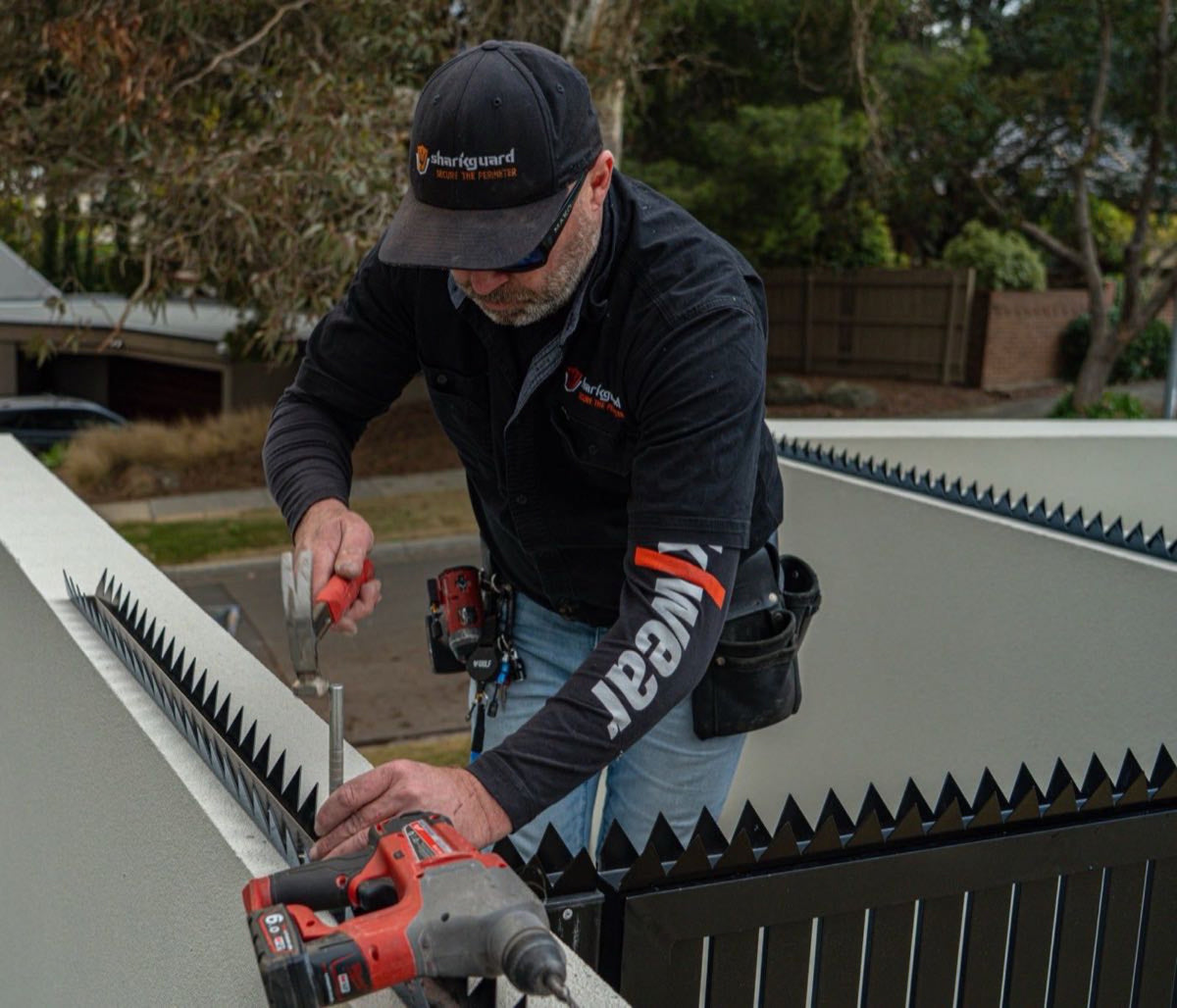 Fence spikes being fitted to a steel rail with a cordless drill